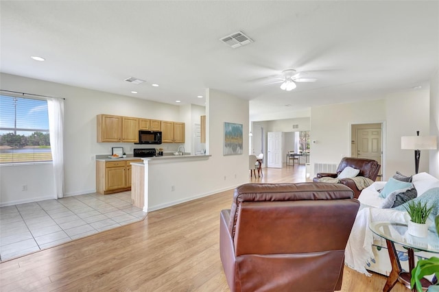 living area with baseboards, ceiling fan, light wood finished floors, and visible vents