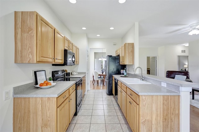kitchen with a sink, light brown cabinets, light countertops, a peninsula, and black appliances
