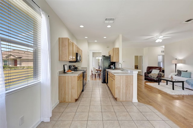 kitchen featuring light brown cabinets, visible vents, black appliances, and open floor plan