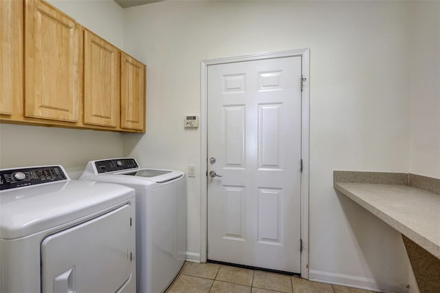 clothes washing area featuring light tile patterned floors, baseboards, cabinet space, and washer and dryer