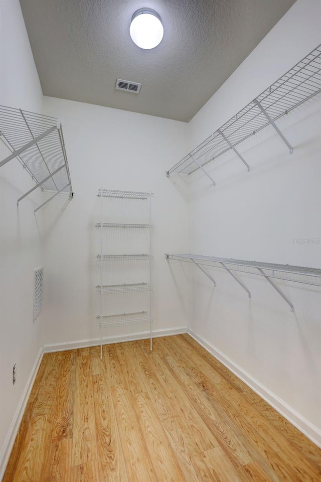 spacious closet featuring light wood-type flooring and visible vents