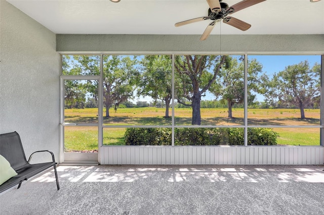 unfurnished sunroom featuring ceiling fan and a wealth of natural light