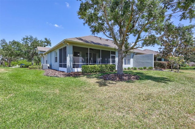 rear view of property featuring a lawn, stucco siding, a sunroom, and roof with shingles