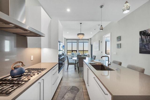 33 S Palm Ave Unit 1403, Sarasota, FL 34236 - kitchen featuring stainless steel gas cooktop, black oven, wall chimney exhaust hood, white cabinetry, and a center island with sink