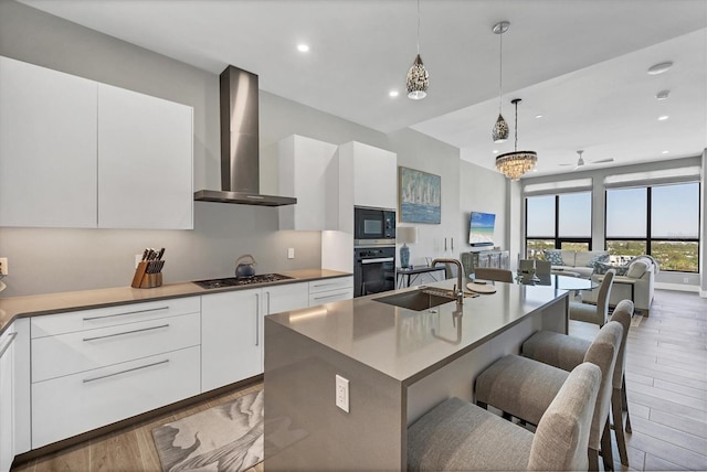 33 S Palm Ave Unit 1403, Sarasota, FL 34236 - kitchen with modern cabinets, wood finished floors, a sink, black appliances, and wall chimney exhaust hood