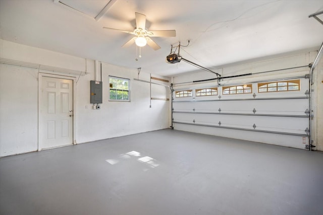 garage featuring a garage door opener, a ceiling fan, and electric panel