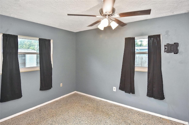 unfurnished room featuring baseboards, a ceiling fan, and a textured ceiling