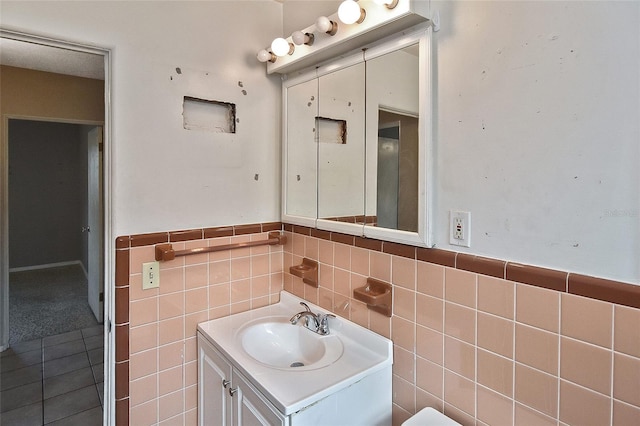 bathroom with vanity, a wainscoted wall, and tile walls