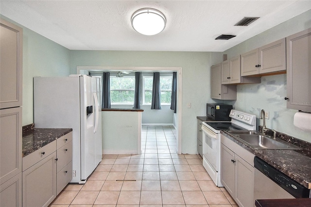 kitchen with visible vents, a sink, dark countertops, and white appliances