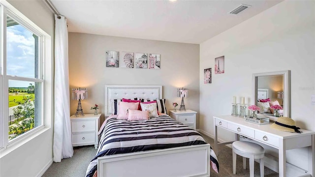 bedroom with carpet floors, visible vents, and multiple windows