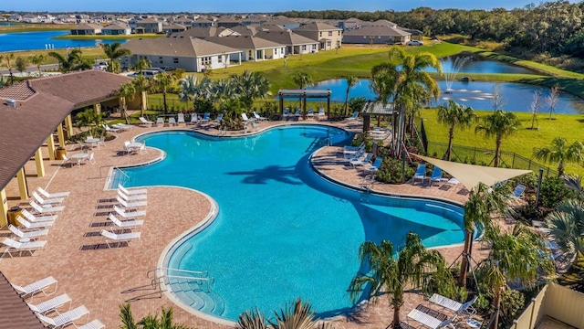 community pool featuring fence, a residential view, a pergola, a water view, and a patio