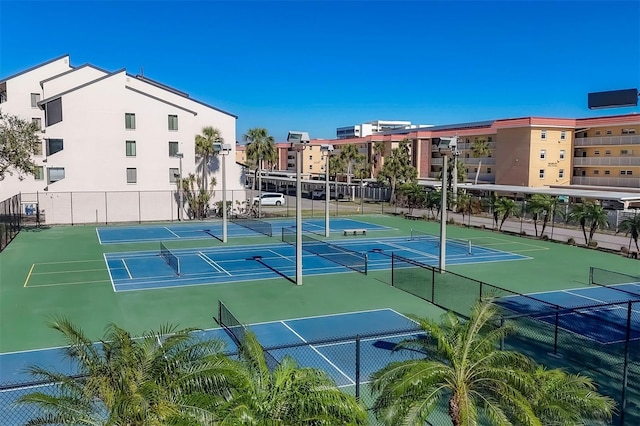 view of tennis court with community basketball court and fence