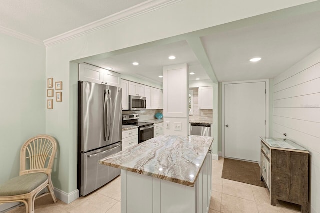 kitchen with stainless steel appliances, white cabinets, light tile patterned flooring, light stone counters, and ornamental molding