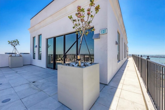 exterior space with stucco siding, a patio area, and a water view