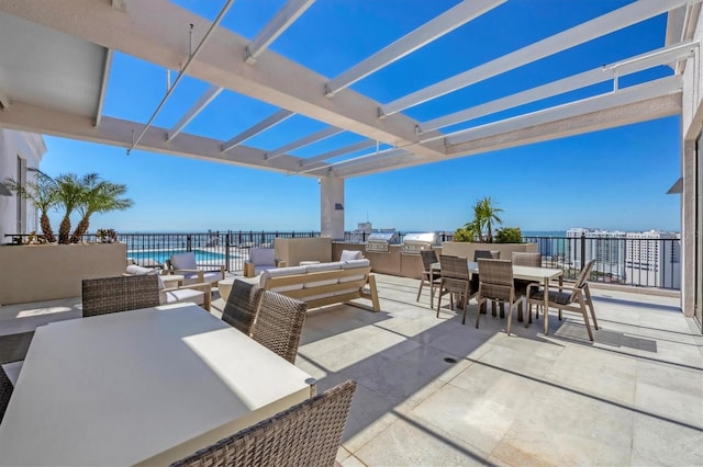 view of patio with outdoor dining space, exterior kitchen, a pergola, and a water view