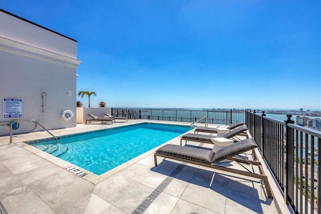 community pool with a patio area and a water view