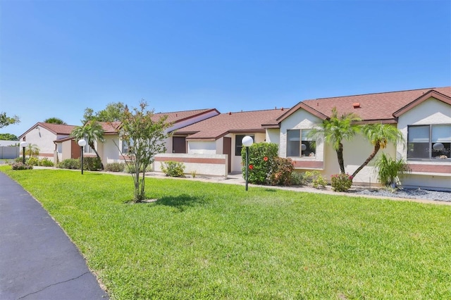 ranch-style home with a front yard and stucco siding