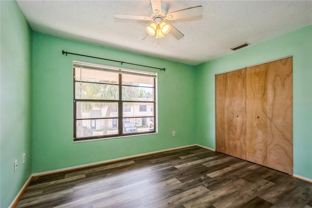 3610 54th St W Unit B4, Bradenton, FL 34209 - unfurnished bedroom with dark wood-style floors, a textured ceiling, a closet, baseboards, and a ceiling fan