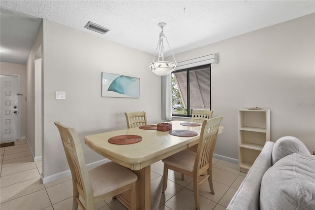 dining room featuring light tile patterned flooring, baseboards, and a textured ceiling