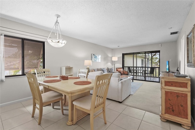 dining space featuring light tile patterned floors, a textured ceiling, and baseboards