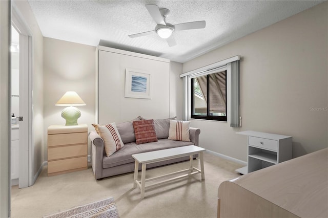 bedroom with a textured ceiling, light colored carpet, a ceiling fan, and baseboards
