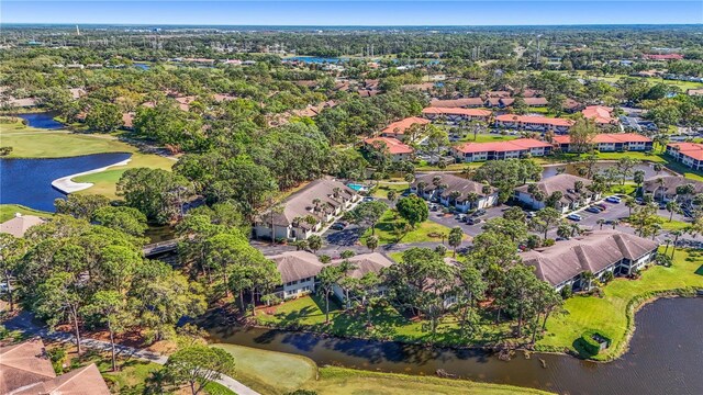 aerial view of property's location featuring a golf course, a large body of water, and nearby suburban area