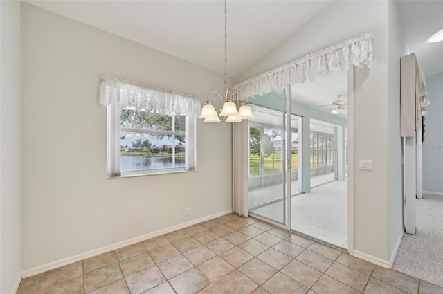 unfurnished dining area featuring a chandelier, vaulted ceiling, tile patterned flooring, baseboards, and a ceiling fan