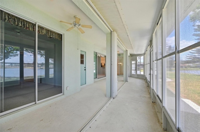 unfurnished sunroom featuring ceiling fan and a water view