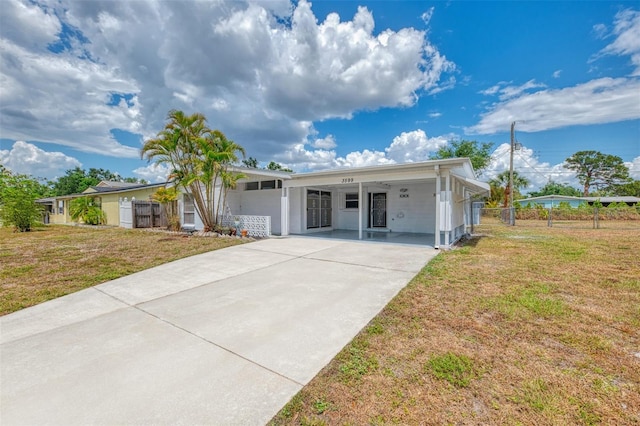 single story home with a front lawn, fence, driveway, and an attached carport