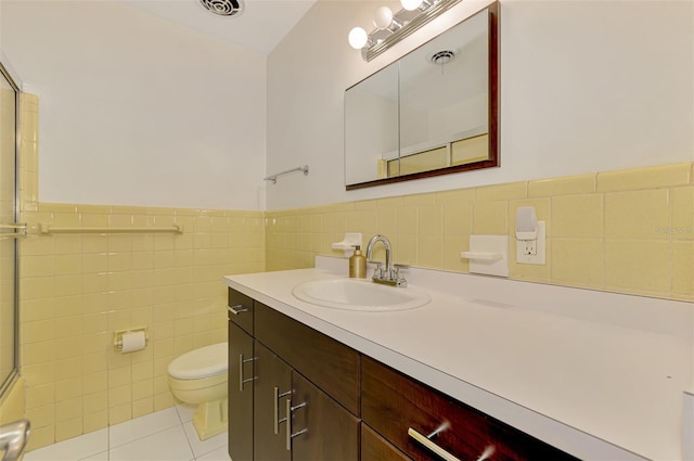 full bath with vanity, toilet, tile walls, a wainscoted wall, and tile patterned floors