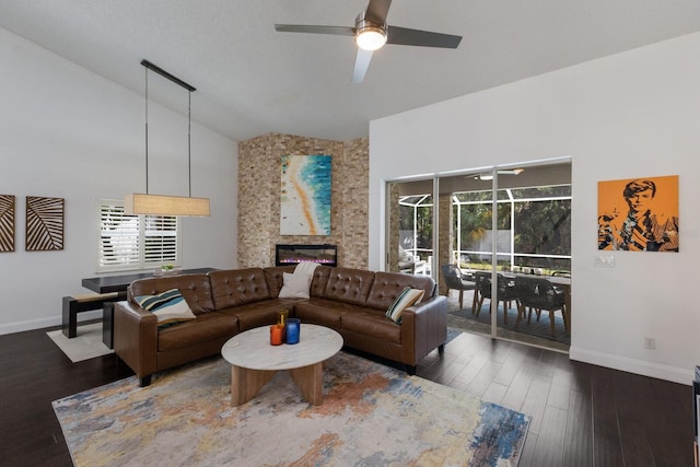 living area featuring a ceiling fan, a fireplace, wood finished floors, baseboards, and high vaulted ceiling