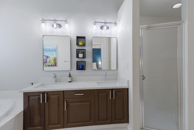 full bathroom with double vanity, a shower stall, and a sink