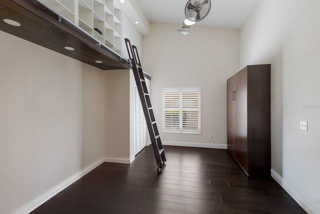 interior space featuring baseboards, hardwood / wood-style floors, and a towering ceiling
