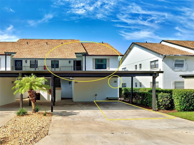 view of property with covered parking, roof with shingles, and stucco siding