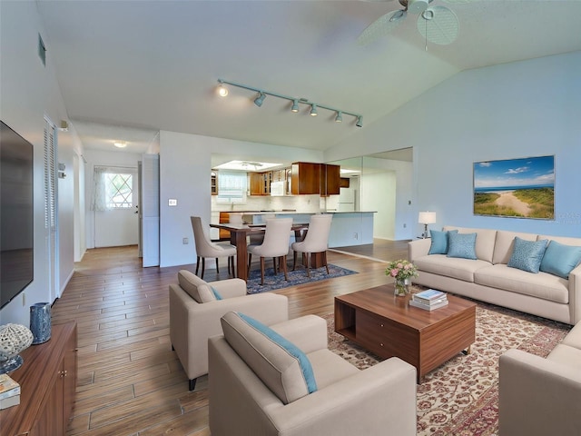 living room featuring visible vents, wood finished floors, ceiling fan, rail lighting, and vaulted ceiling