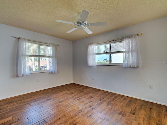 empty room with a textured ceiling, wood finished floors, and a wealth of natural light
