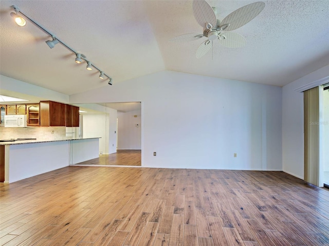 unfurnished living room featuring track lighting, a ceiling fan, vaulted ceiling, and light wood finished floors