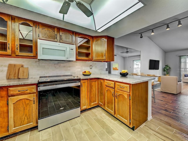 kitchen featuring a ceiling fan, white microwave, stainless steel electric stove, and vaulted ceiling