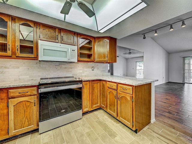 kitchen featuring a ceiling fan, electric range, lofted ceiling, and white microwave