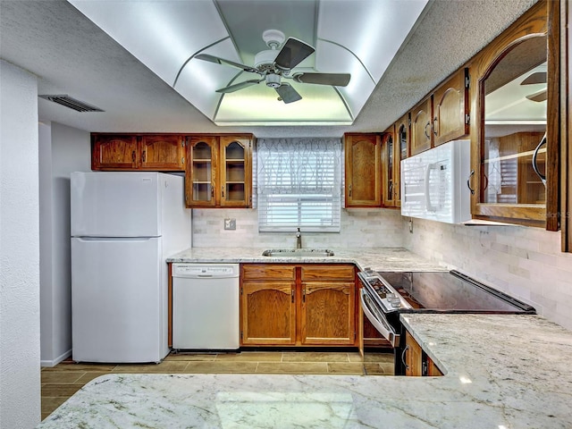 kitchen with a sink, ceiling fan, white appliances, and tasteful backsplash