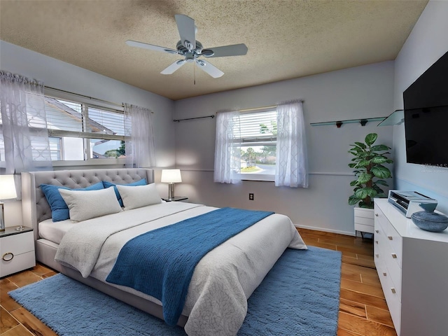 bedroom with baseboards, a ceiling fan, a textured ceiling, and wood finished floors