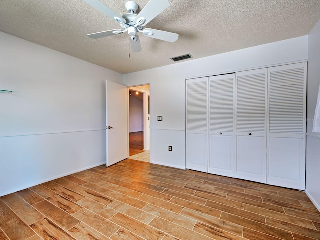 unfurnished bedroom with visible vents, a closet, wood finished floors, ceiling fan, and a textured ceiling
