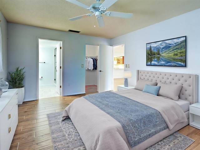 bedroom with visible vents, a closet, wood finished floors, ensuite bathroom, and a spacious closet