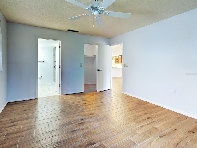 interior space with baseboards, ceiling fan, wood finished floors, and visible vents
