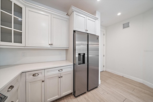 555 N Orange Ave Unit 307, Sarasota, FL 34236 - kitchen featuring stainless steel fridge, light countertops, baseboards, glass insert cabinets, and light wood-type flooring