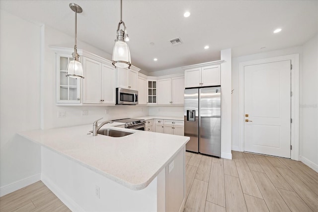 555 N Orange Ave Unit 307, Sarasota, FL 34236 - kitchen featuring appliances with stainless steel finishes, a sink, light countertops, glass insert cabinets, and a peninsula