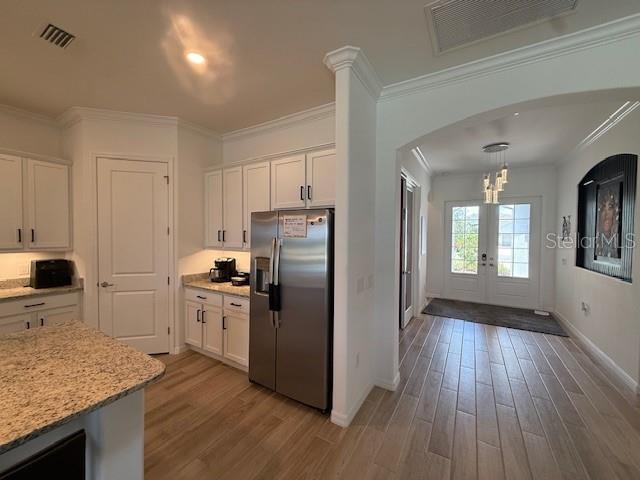 kitchen featuring white cabinetry, stainless steel fridge, arched walkways, and visible vents