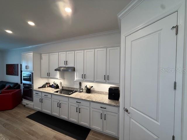 kitchen featuring black electric stovetop, light wood finished floors, crown molding, and under cabinet range hood