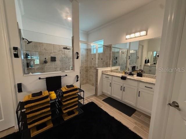 full bathroom featuring a stall shower, vanity, crown molding, and wood finished floors