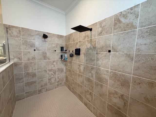 full bathroom with ornamental molding and tiled shower
